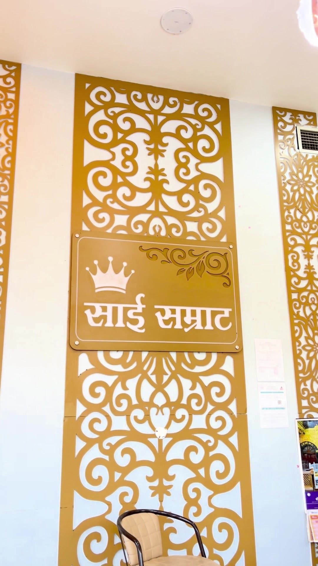 Gold jaali panel with the Sai Samrat name at reception